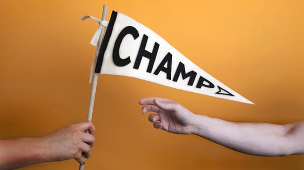 Image of someone giving a flag to another person. The flag has "Champ" written on it.