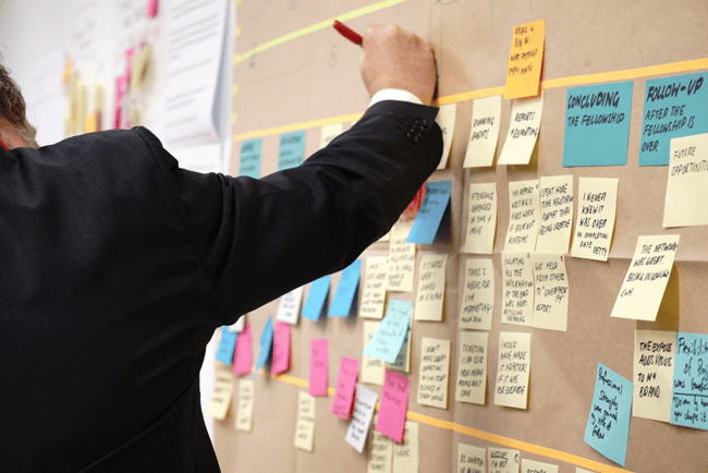 managing a project, man writes on post-it notes on a wall